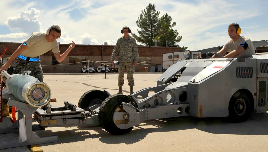 HOLLOMAN AIR FORCE BASE, N.M. -- Weapon load crew members from the 49th Aircraft Maintenance Squadron position an MJ-1 bomb lift truck under a Guided Bomb Unit 12 before transporting it to an MQ-9 Reaper during the Weapons Load Crew Competition July 30, 2010. This friendly competition, held every quarter, requires crew members to load F-22 Raptors and MQ-9 Reapers with munitions within 30 minutes. Winners from each crew get plaques as well as a traveling trophy. (U.S. Air Force photo by Senior Airman Veronica Stamps/ Released)