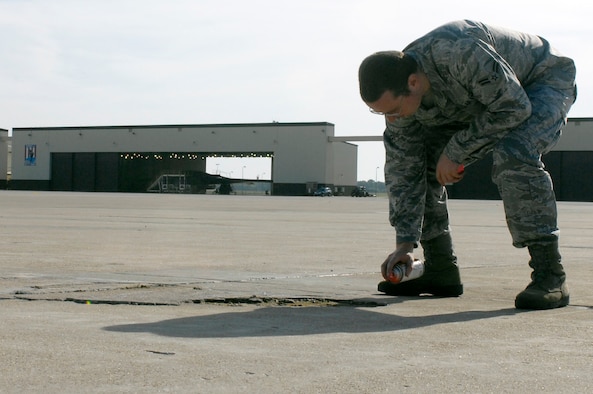 WHITEMAN AIR FORCE BASE, Mo. - Airman 1st Class Brandon Mills, 509th Operations Support Squadron airfield management, marks a portion of the flightline that requires maintenance, Aug. 4. Cracked concrete can cause foreign object debris on the flightline and can hinder flightline operations. Airfield management personnel conduct numerous checks throughout the day to prevent FOD. (U.S. Air Force photo/Senior Airman Jason Barebo)