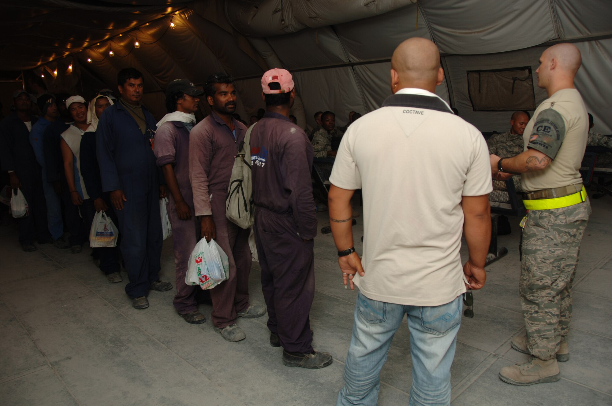 SOUTHWEST ASIA -- Third Country Nationals wait in line for Staff Sgt. Jamie Viau, 379th Expeditionary Civil Engineer Squadron TCN Escort Victor Lead, to assign escorts to them.  The TCNs go through this process every morning before reporting  to various construction sites around the installation here. (U.S. Air Force photo/Tech. Sgt. Kimberly Spinner)