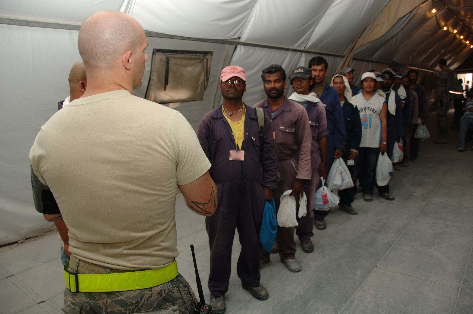 SOUTHWEST ASIA -- Third Country Nationals wait in line for Staff Sgt. Jamie Viau, 379th Expeditionary Civil Engineer Squadron TCN Escort Victor Lead, to assign escorts to them. The TCNs go through this process every morning before reporting to various construction sites around the installation here. (U.S. Air Force photo/Tech. Sgt. Kimberly Spinner)