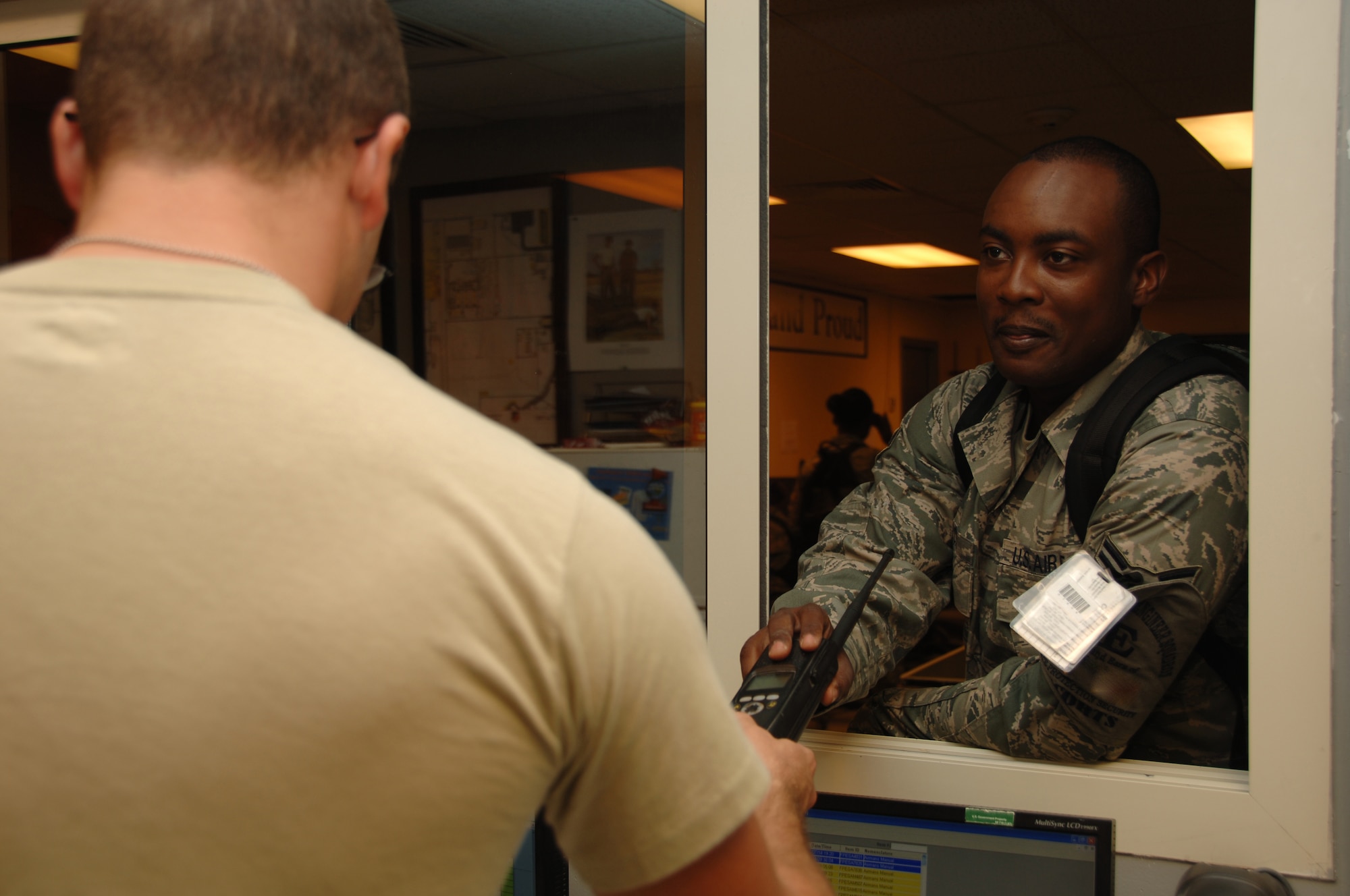 SOUTHWEST ASIA -- Senior Airman Trebor Lewis (left) issues Airman 1st Class Thomas Gleaton a radio at the start of his shift here August 3. Airmen Lewis and Gleaton are Third Country National escorts with the 379th Expeditionary Civil Engineer Squadron. (U.S. Air Force photo/Tech. Sgt. Kimberly Spinner)