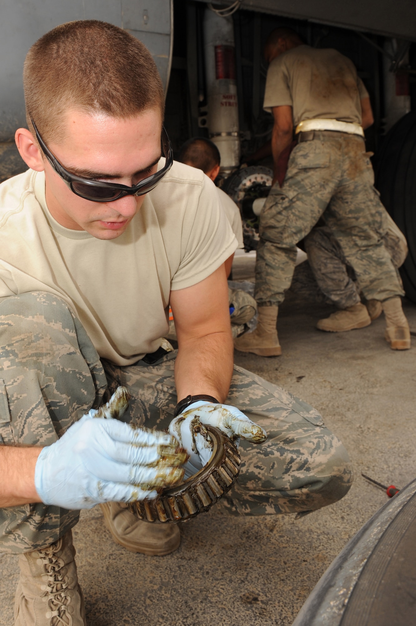 Airman 1st Evan Morter, a crew chief assigned to the 451st Expeditionary Aircraft Maintenance Squadron, Kandahar Airfield, Afghanistan, greases ball bearings from a C-130J Hercules wheel assembly Aug. 2, 2010.  Airman Morter is preparing to replace the wheel after it was removed during maintenance.  (U.S. Air Force photo by Tech. Sgt. Chad Chisholm/Released)
