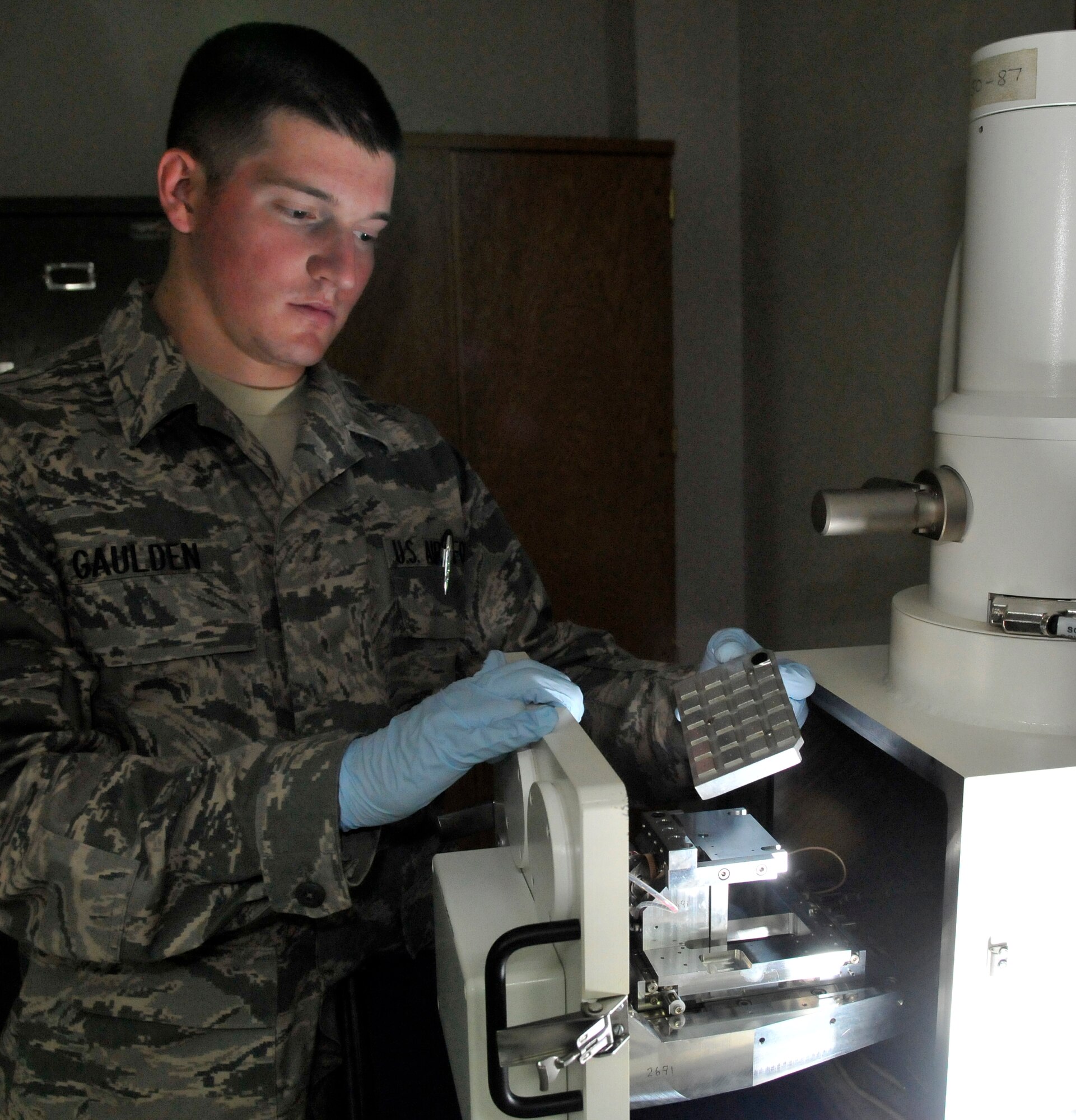Senior Airman Jonathan Gaulden, 332nd Expeditionary Maintenance Squadron Non-Destructive Inspection Lab technician, loads a test tray into a chip detector to test for wear metals July 28, 2010, Joint Base Balad, Iraq. The chip detector is an electron microscope that detects the presence of contaminates in engine oil. Airman Gaulden is a native of Rockhill, S.C., deployed from McEntyre Air National Guard Station, S.C. (U.S. Air Force photo/Staff Sgt. Phillip Butterfield)