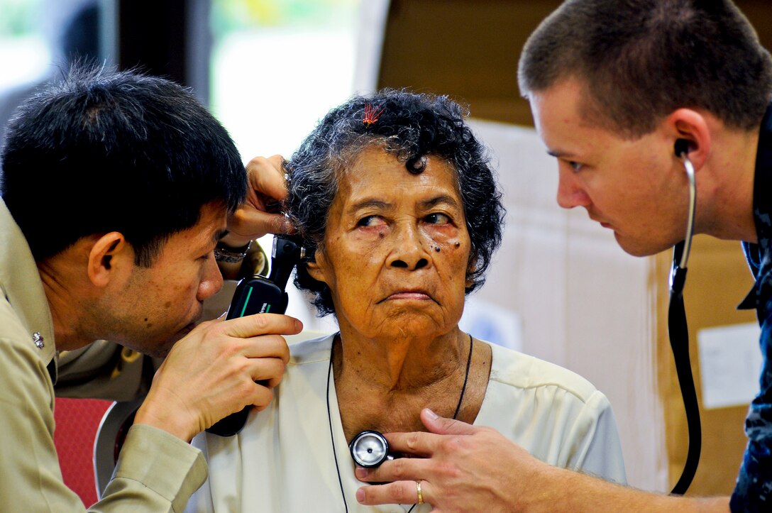U.S. Navy Cmdr. Tri Lac and Petty Officer 2nd Class Scott Peterson perform a medical exam on woman at a medical clinic event at Ngarachemayong Community Center in Koror, Palau, July 29, 2010. Lac and Peterson are assigned to the USS Blue Ridge.