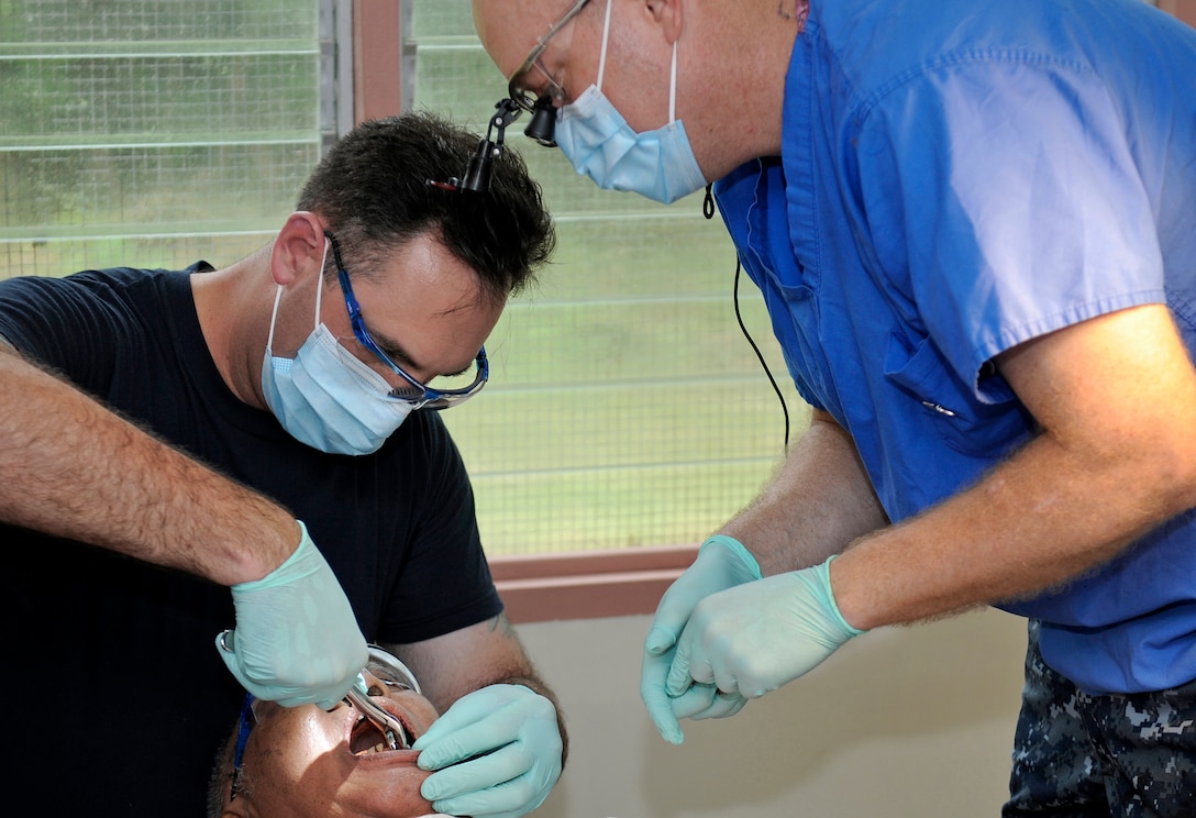 U.S. Navy Senior Chief Petty Officer Christopher Moore, left, extracts a patient's tooth under the supervision of Lt. Shawn Teutsch at the Angaur Medical Clinic in Angaur, Palau, July 29, 2010. Moore and Teutsch are assigned to the USS Blue Ridge. 
