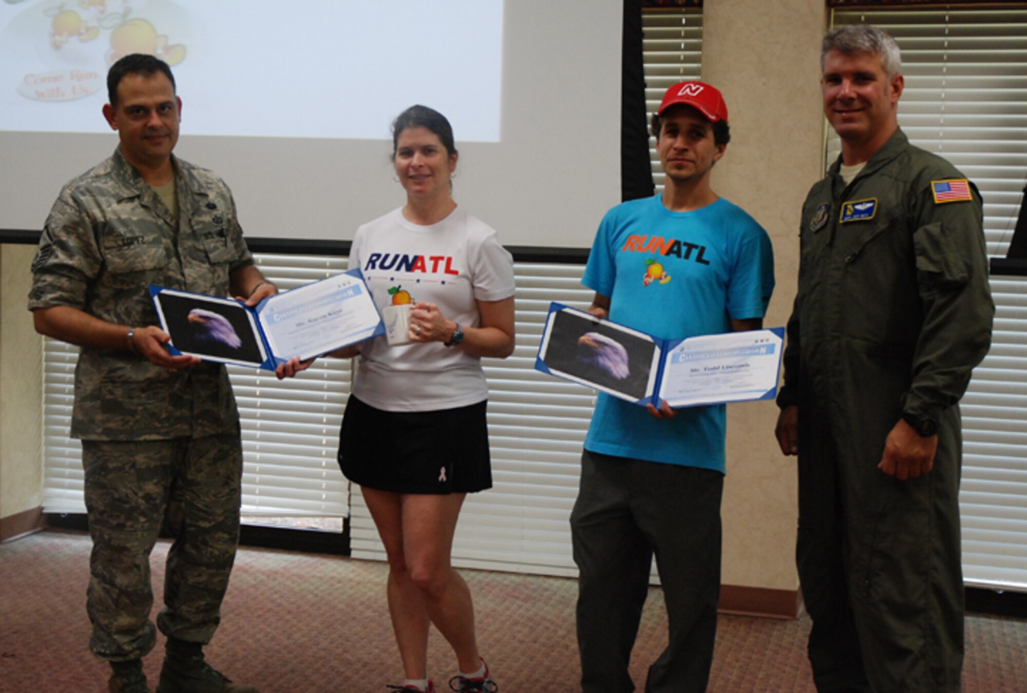 Master Sgt. Larry Lopez and Master Sgt. Jeff Botz present tokens of appreciation to the staff of Big Peach Running during the Top 3 meeting July 11. Karen Kaye, speed walking and running coach instructed the group on building endurance, sticking to a good physical fitness program and buying running shoes that will best support your body. (U.S. Air Force photo/Master Sgt. James Branch)