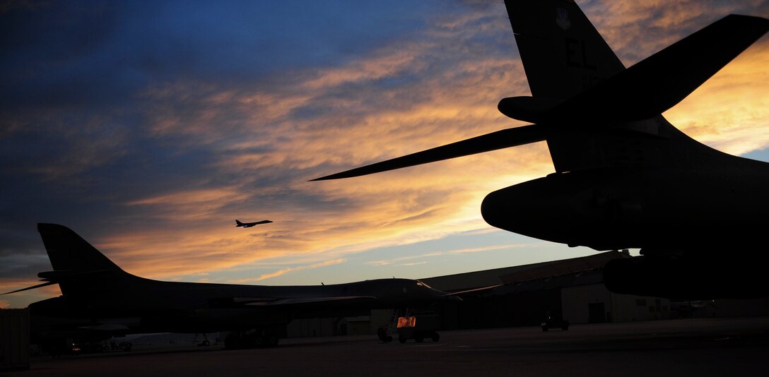 ELLSWORTH AIR FORCE BASE, S.D. - B-1B Lancers sit on the flightline as another B-1 flies overhead, Aug. 3. The B-1 can rapidly deliver massive quantities of precision and nonprecision weapons against any adversary, anywhere in the world. (U.S. Air Force photo/Airman 1st Class Corey Hook) 