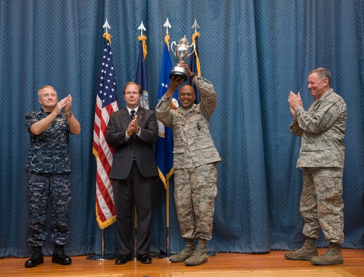 Col. Anthony Cotton, 341st Missile Wing commander, hoists the Omaha Trophy overhead in a ceremony at the base theater Aug. 3. On stage with the colonel (left to right) are Vice Adm. Carl Mauney, USSTRATCOM deputy commander; John Whisler, Jr., Senior Vice President of Omaha-based Leo A. Daly Architectural Engineering firm; and Maj. Gen. C. Donald Alston, 20th Air Force commander. This is the third consecutive year Malmstrom has earned the prestigious award. (U.S. AIr Force photo/Beau Wade)