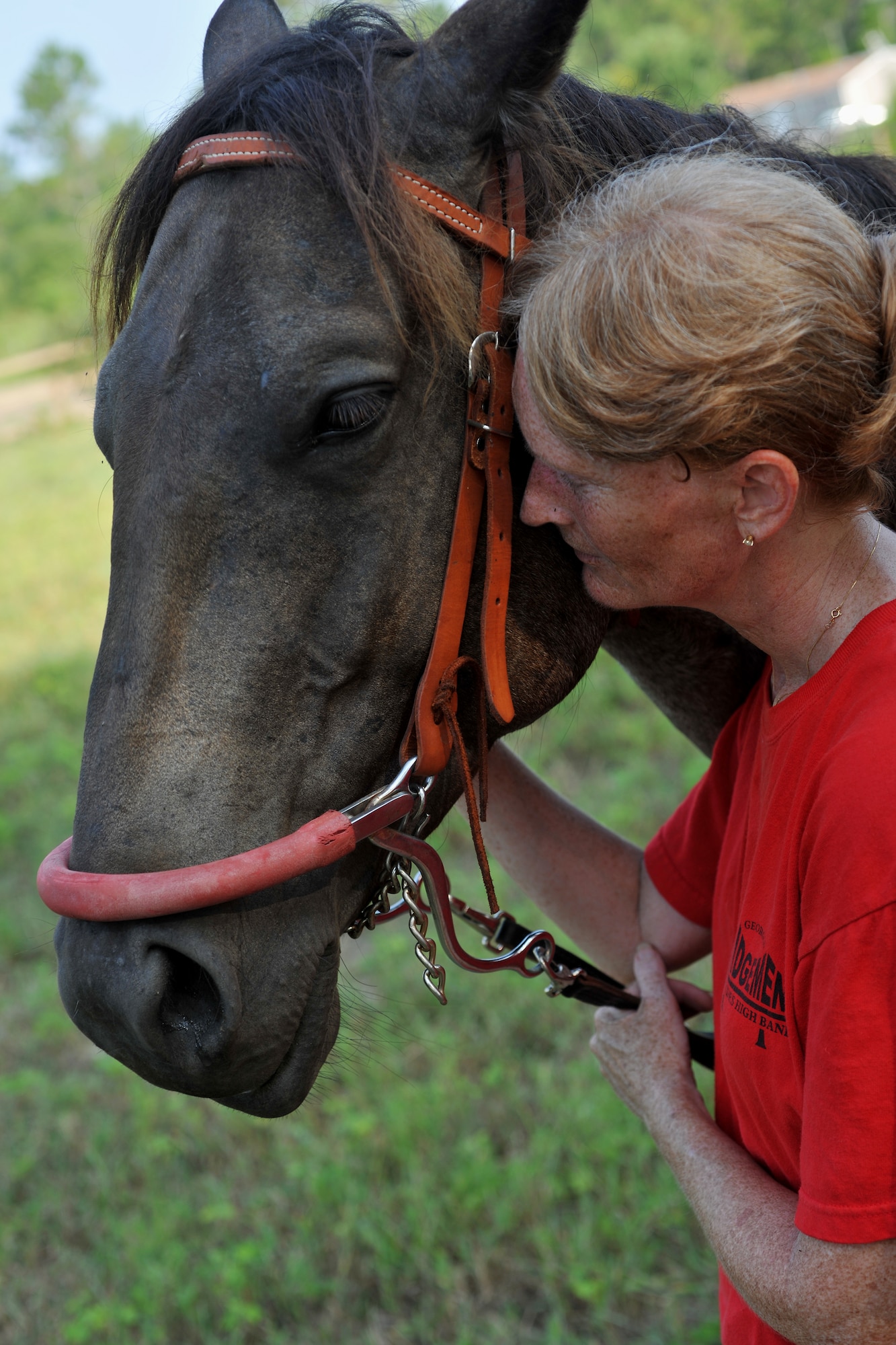 QUITMAN, Ga. -- Maj. Laurie Abney, 23rd Medical Group education and training flight commander at Moody Air Force Base, Ga., pulls the face of Blue, a riding horse, into hers during a moment of relaxation at the Hopes and Dream Riding Facility here July 31. The Hopes and Dreams Riding Facility is a therapeutic horseback riding program and is an activity which has been proven to help relieve symptoms of brain trauma and stress-related disorders in many people, including combat veterans. (U.S. Air Force photo by Airman 1st Class Joshua Green/RELEASED)