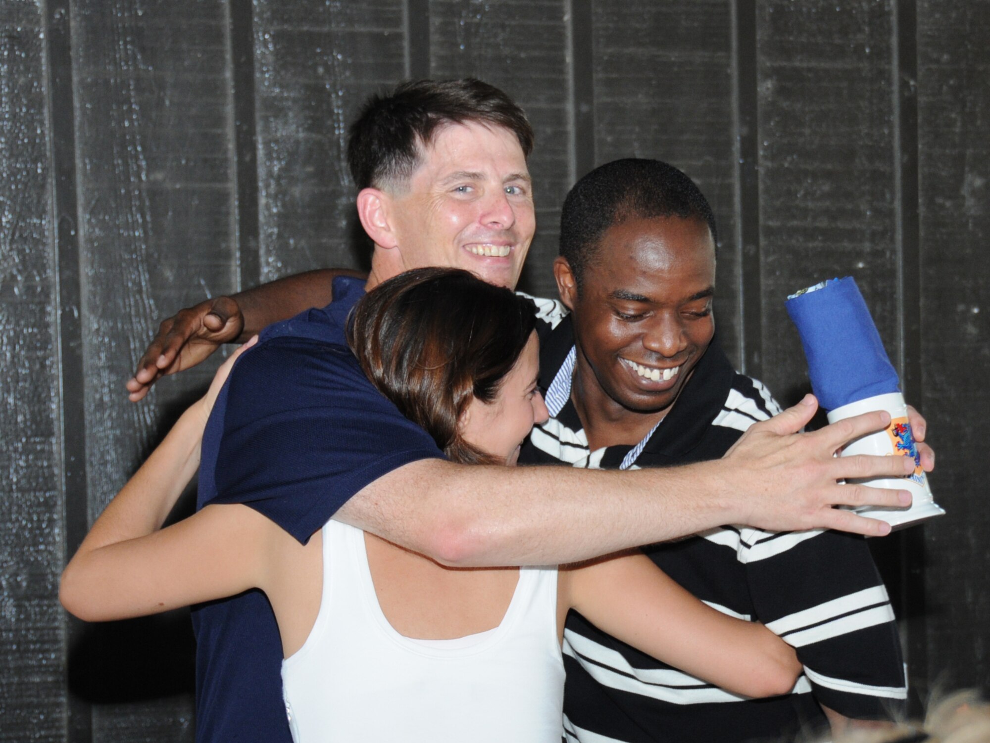 Brig. Gen. Ian Dickinson, outgoing 81st Training Wing commander, gets a gift and a hug from Capts. Donna Burrowes, vice president, and Jermaine Jordan, president of the company grade officers council, at a going-away barbecue Sunday at marina park. (U.S. Air Force photo by Kemberly Groue)