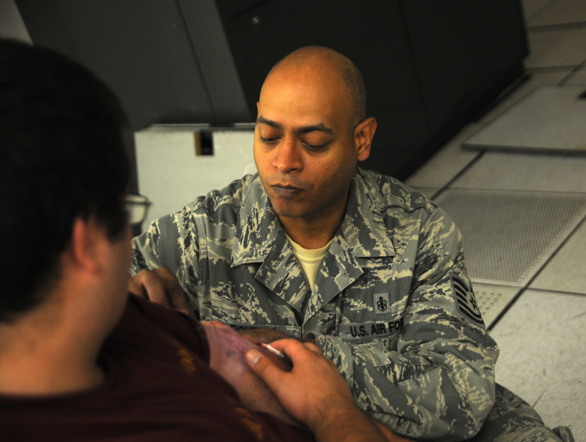 Tech. Sgt. Victor Figueroa, a 421st Combat Training Squadron medic, applies makeup to simulate an arm wound on a civilan role player before the start of a scenario for Eagle Flag Aug. 5 at Joint Base McGuire-Dix-Lakehurst.  The exercise tested emergency officials’ ability to respond to a hurricane in New Jersey. (U.S. Air Force photo by Staff Sgt. Zachary Wilson/Released.)