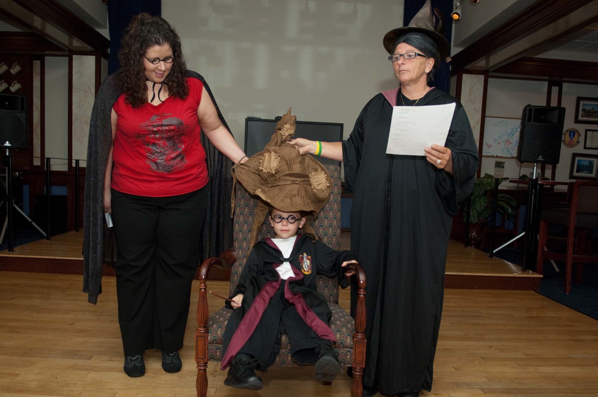 HANSCOM AIR FORCE BASE, Mass. – Nathan Massie, a new student of wizardry, tries on the Sorting Hat while Professors Hooch (left) and McGonagall assist. The Sorting Hat determined the seating arrangements at Saturday’s Harry Potter themed banquet at the club. (U.S. Air Force photo by Rick Berry)