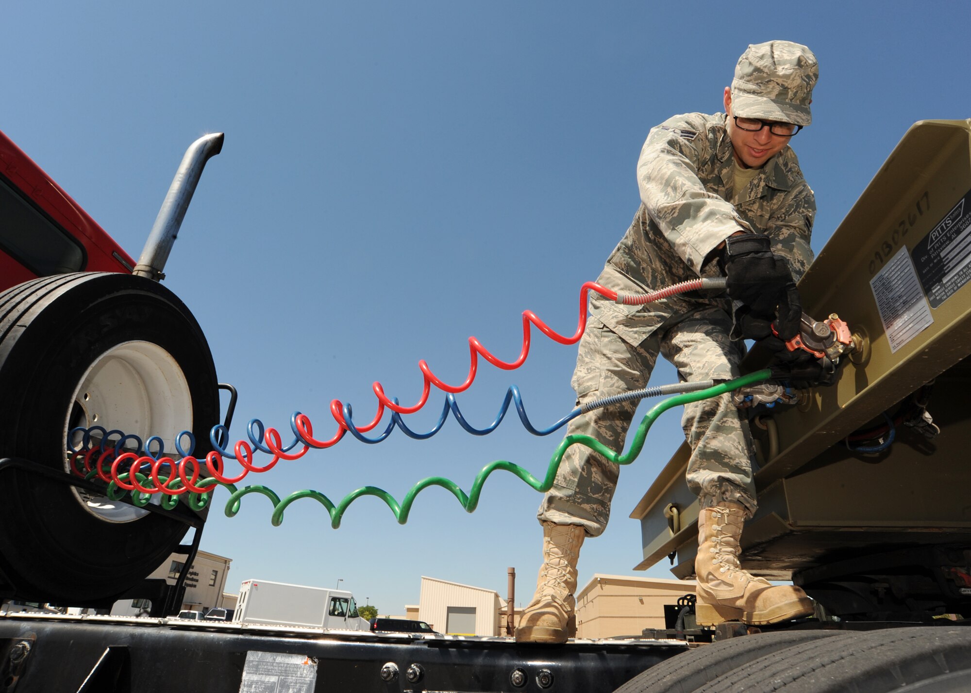 Airman 1st Johnny Ortiz, 22nd Logistics Readiness Squadron vehicle operator dispatcher, couples electrical and brake air lines from a tractor to a trailer Aug. 3, 2010, McConnell Air Force Base, Kan.  Vehicles, like the tractor, are used to do cargo sweeps on base every day. One person averages approximately 389 parts at a net worth of $156,000 total.  Vehicle operations personnel work Monday through Friday, 24 hours a day, and weekends from 7 a.m. to 12 a.m. and have stand by personnel for emergencies.  (U.S. Air Force photo/Senior Airman Maria Ruiz)