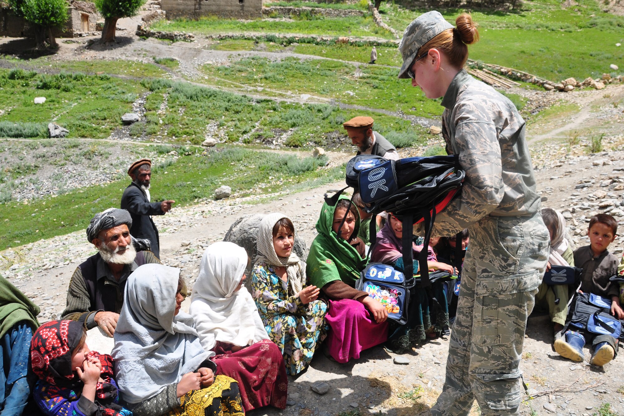 U.S. Air Force Tech. Sgt. Carolyn McIlvaine, Westfield, Mass., native and Provincial Reconstruction Team Panjshir medical team non-commissioned officer in charge, hands out book bags to girls in the village of Kohe-sur. PRT Panjshir met with the Paryan District Development Assembly for women's affairs to discuss various projects and make a humanitarian drop to a girls' school in the Paryan District. (Photo by U.S. Air Force 1st Lt. Holly A. Hess, PRT Panjshir Public Affairs)