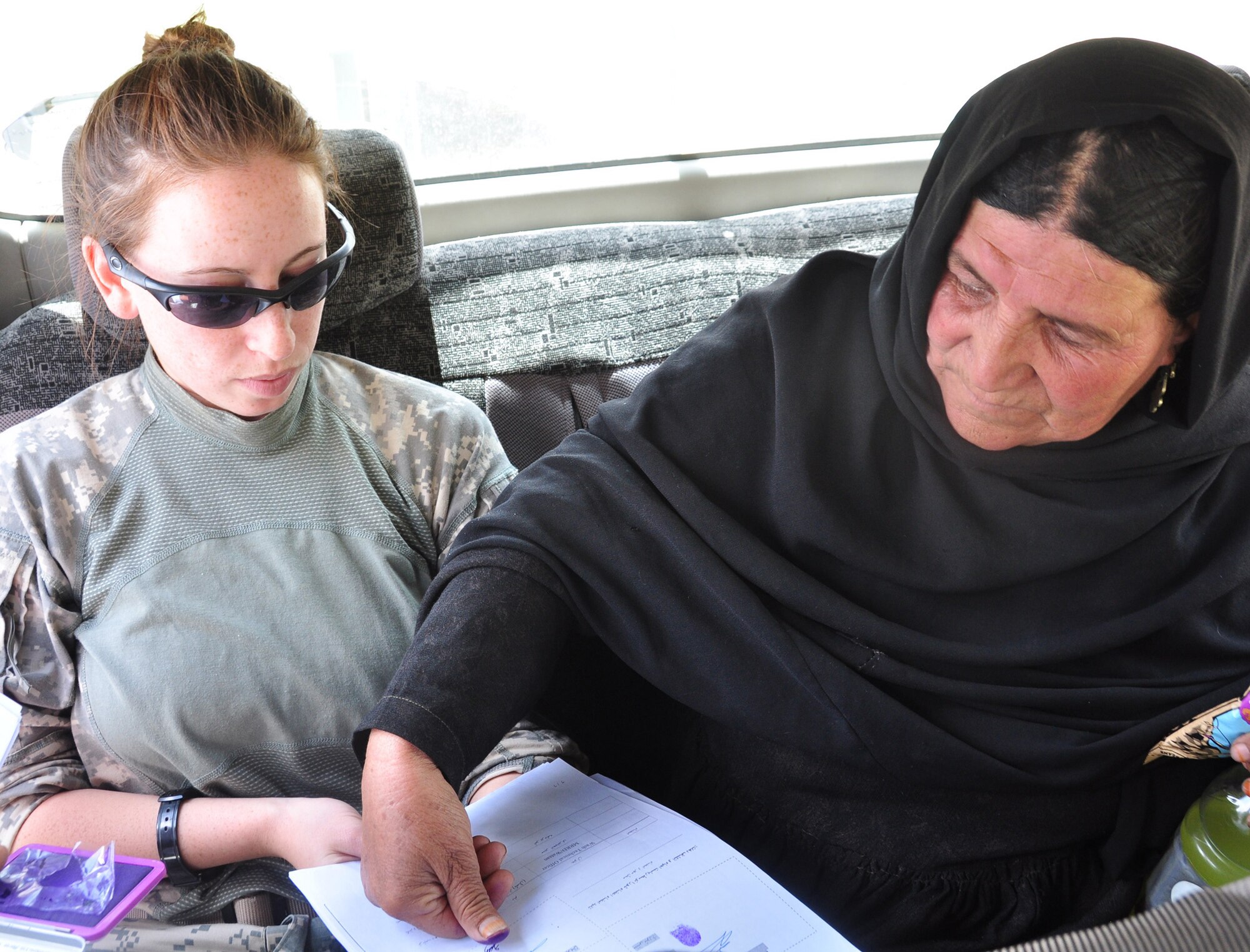 U.S. Army Spc. Allison Cherkosly, Clifton Park, N.Y., native and Provincial Reconstruction Team Panjshir civil affairs member, assists Annisa Gul, District Development Assembly for women?s affairs in the Paryan District, by holding paperwork while Gul signs the document with her thumb print. PRT Panjshir met with Gul to discuss various women's affairs projects and to make a humanitarian drop to a girls' school in the Paryan District. (Photo by U.S. Air Force 1st Lt. Holly A. Hess, PRT Panjshir Public Affairs)