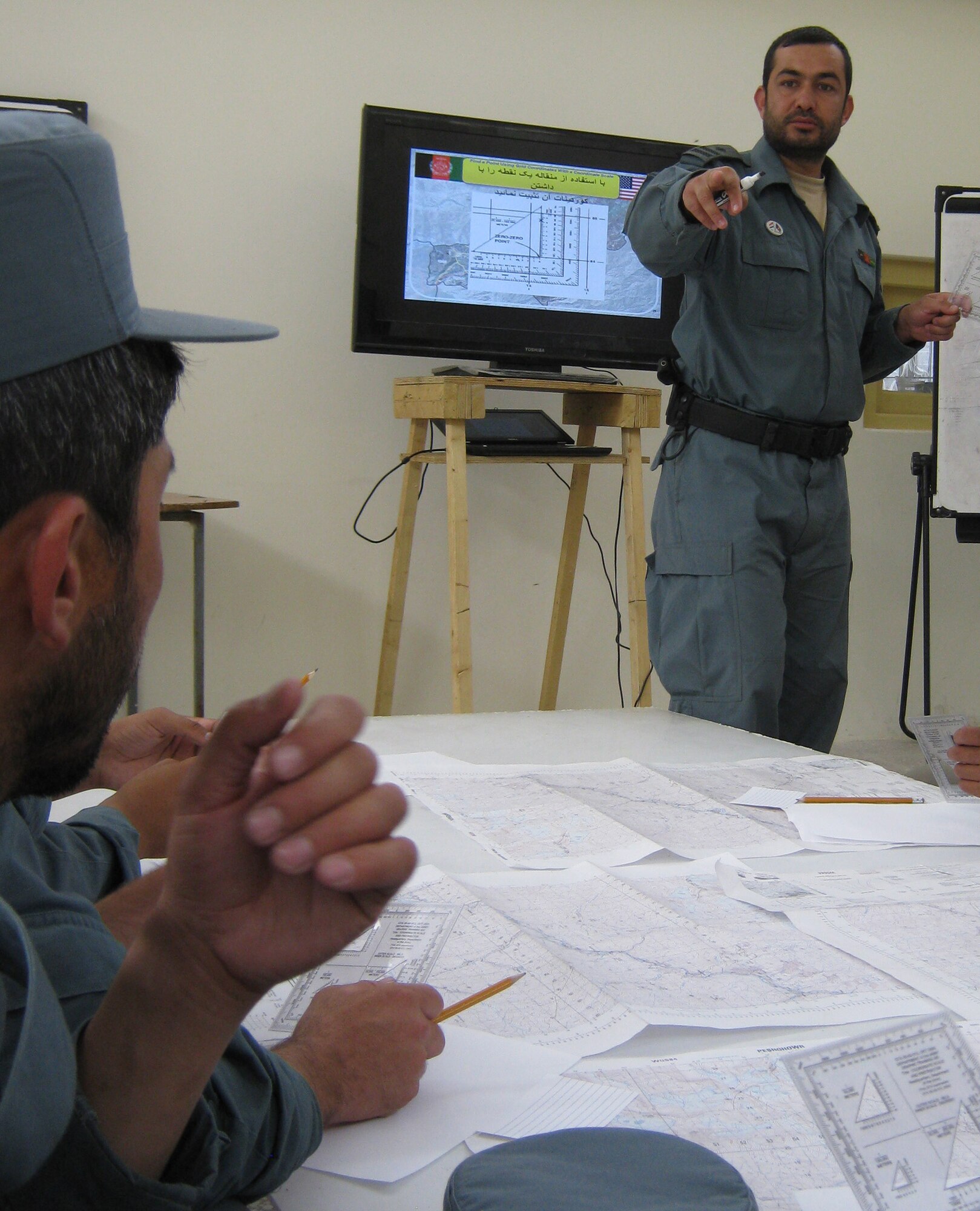 Afghan National Police Capt. Safat Ullah Sangee, Panjshir Operations Coordination Center-Provincial, teaches a map and compass reading techniques class July 13. This class was the second day of Sangee?s three-day course at the Rokha Police Headquarters. Some of the things Sangee taught included how to use a protractor with a map, give grid coordinates, find grid coordinates, identify terrain features and measure distance between points. (Photo by U.S. Air Force 2nd Lt. Jason Smith, PRT Panjshir Public Affairs)