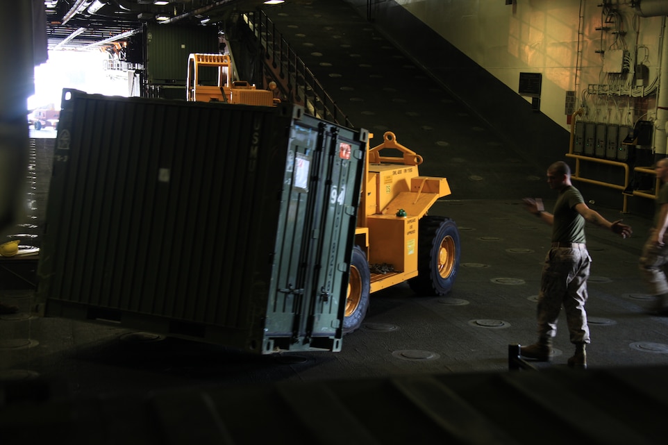 Combat Cargo Marines with 26th Marine Expeditionary Unit aboard USS Kearsarge move a quadruple container (QUADCON) into place. The Marines prepared to move more than 1,111 tons worth of vehicles and other cargo Aug. 6, 2010. Combat Cargo Marines are responsible for all gear and vehicles being loaded and stowed aboard the ships of Kearsarge Amphibious Ready Group. 26th MEU deployed aboard the ships of Kearsarge Amphibious Ready Group in late August responding to an order by the Secretary of Defense to support Pakistan flood relief efforts.