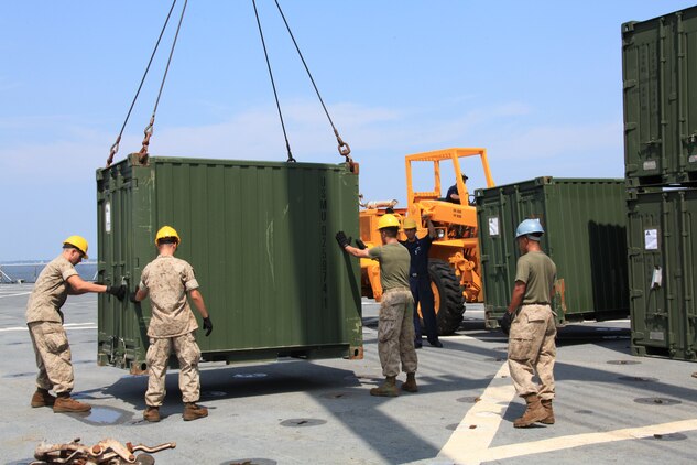 Combat Cargo Marines with 26th Marine Expeditionary Unit aboard USS Carter Hall guide quadruple container (QUADCON) to its resting place Aug. 6, 2010. Combat Cargo Marines are responsible for all gear and vehicles being loaded and stowed aboard the ships of Kearsarge Amphibious Ready Group. 26th MEU deployed aboard the ships of Kearsarge Amphibious Ready Group in late August responding to an order by the Secretary of Defense to support Pakistan flood relief efforts.