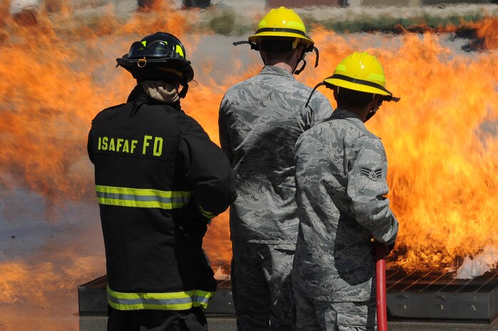 Capt. Brad Myers, a fire fighter at Creech Air Force Base, observes two Airmen extinguishing a fire during the inaugural fire fighting training course held at Creech Aug. 7. The Creech fire department trained members of the 99th GCTS on basic fire fighting skills to help contain fires at the security forces training site, Silver Flag Alpha. (U.S. Air Force photo by Senior Airman Brian Ybarbo)