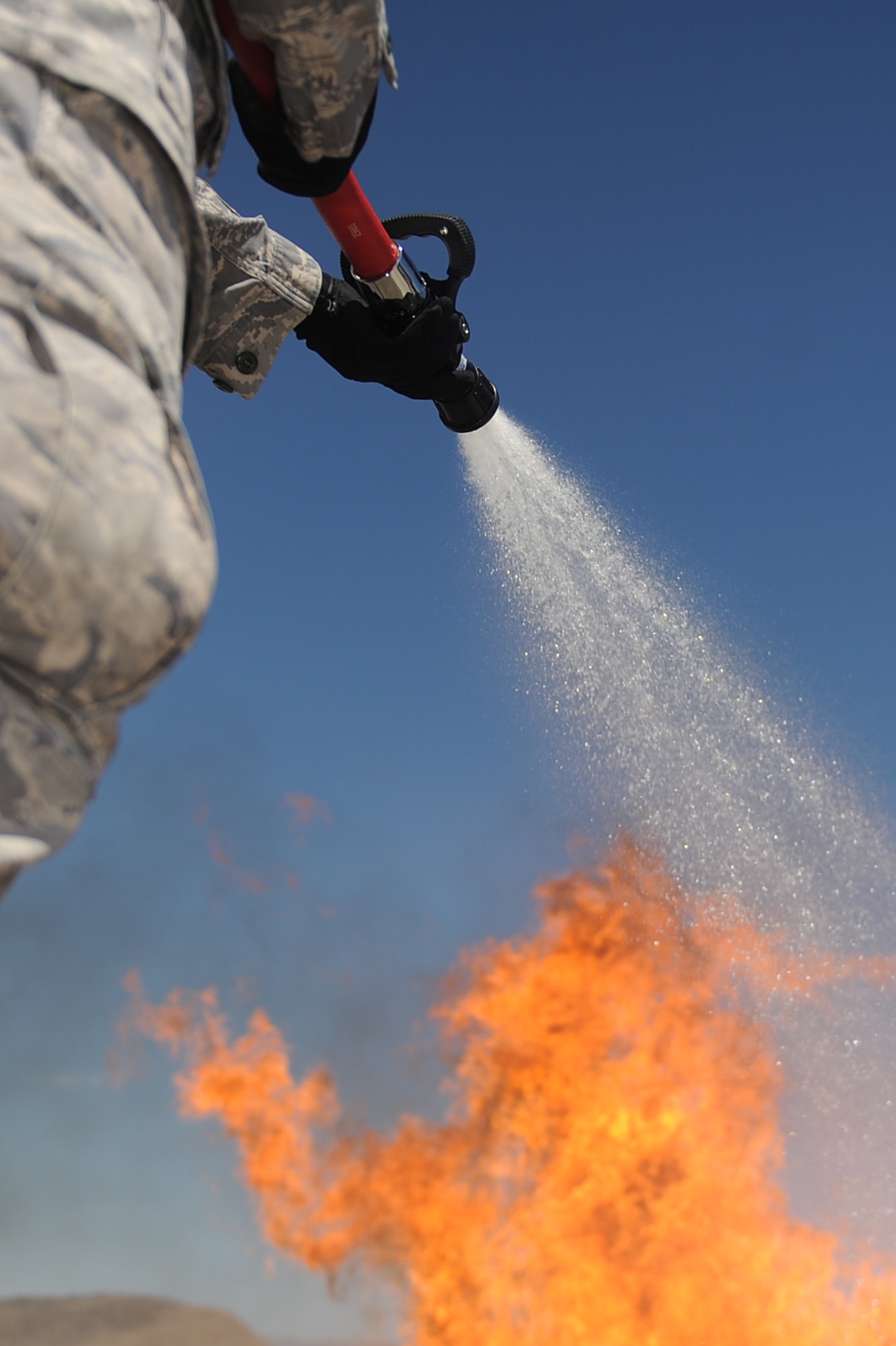 A member of the 99th Ground Combat Training Squadron extinguishes a fire during the inaugural fire fighting training course held at Creech Air Force Base Aug. 7. The Creech fire department trained members of the 99th GCTS on basic fire fighting skills to help contain fires at the security forces training site, Silver Flag Alpha. (U.S. Air Force photo by Senior Airman Brian Ybarbo)