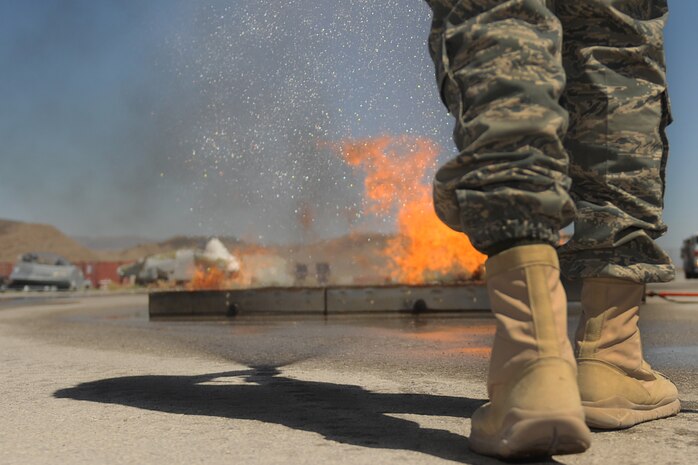 A member of the 99th Ground Combat Training Squadron extinguishes a fire during the inaugural fire fighting training course held at Creech Air Force Base Aug. 7. The Creech fire department trained members of the 99th GCTS on basic fire fighting skills to help contain fires at the security forces training site, Silver Flag Alpha. (U.S. Air Force photo by Senior Airman Brian Ybarbo)