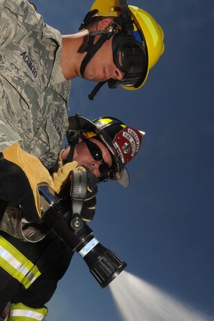 Staff Sgt. Vincent Acunto, a member of the 99th Ground Combat Training Squadron, tests his water hose as Capt. Brad Myers, a fire fighter at Creech Air Force Base, observes during the inaugural fire fighting training course held at Creech Aug. 7. The Creech fire department trained members of the 99th GCTS on basic fire fighting skills to help contain fires at the security forces training site, Silver Flag Alpha. (U.S. Air Force photo by Senior Airman Brian Ybarbo)