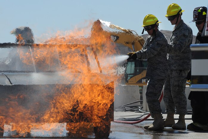 Senior Airman Aaron Alverado and Senior Airman Stephen Ellis, both members of the 99th Ground Combat Training Squadron, put out a fire during the inaugural fire fighting training course held at Creech Air Force Base Aug. 7. The Creech fire department trained members of the 99th GCTS on basic fire fighting skills to help contain fires at the security forces training site, Silver Flag Alpha. (U.S. Air Force photo by Senior Airman Brian Ybarbo)