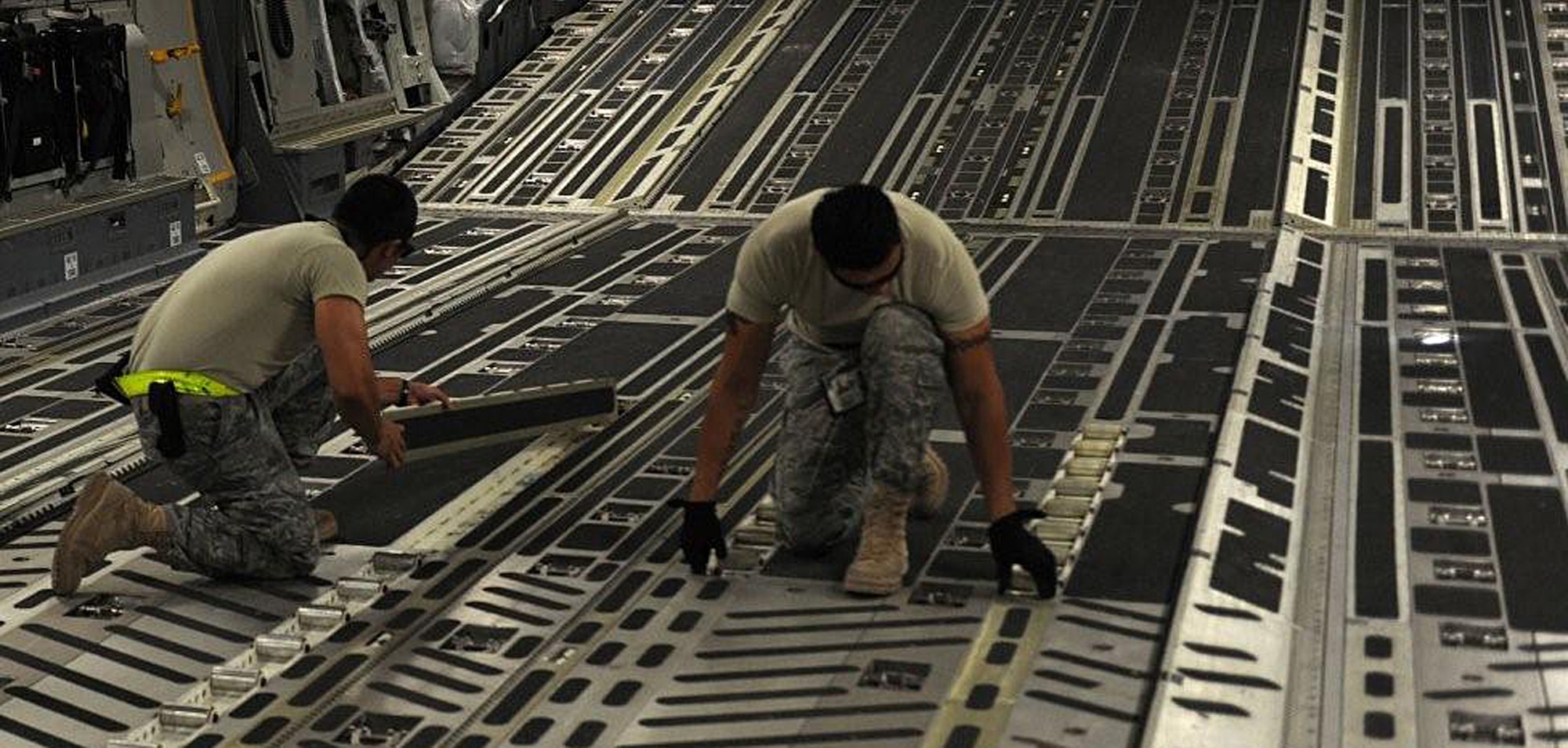 Staff Sgt. Ronald Capalungan, left, and Tech. Sgt. Edwin McCrann reconfigure the cargo floor of a C-17 for pallets of cargo. Sergeants Capalungan and McCrann are Reservists deployed from the 446th Aircraft Maintenance Squadron, Joint Base Lewis-McChord, Wash. (U.S. Air Force photo by Senior Airman Michael Means)