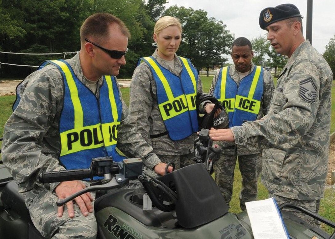 JOINT BASE ANDREWS, Md. -- Senior Master Sgt. Steven Bliss, 316th Security Forces Squadron superintendent of logistics and readiness, right, shows Col. Ken Rizer, 316th Wing/Joint Base Andrews commander, left, 1st Lt. Margot Capell, 316th Wing commander executive, center, and Chief Master Sgt. Anthony Brinkley, 316th Wing/Joint Base Andrews command chief, how to use an All Terrain Vehicle on Joint Base Andrews, Aug. 3. Colonel Rizer and Chief Master Sgt. Brinkley use ATV’s to inspect the fence line around Andrews’ perimeter.   (U.S. Air Force photo by Senior Airman Melissa Brownstein) 