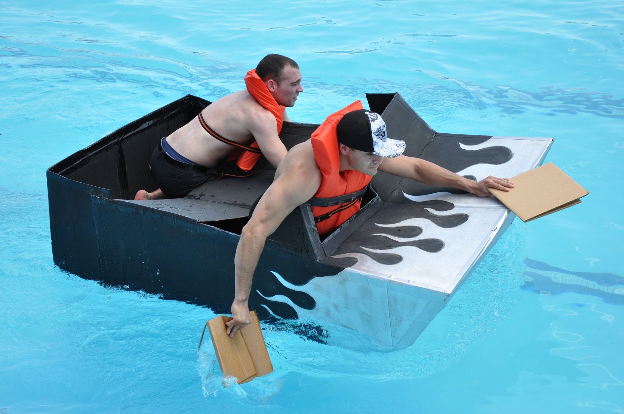 Jimmy Salinas, right, and Joshua Graver, of team Mid Checkers, paddle their way down the Gerrity Pool lane July 31 during the 10th Annual Cardboard Regatta. Team Mid Checkers had the fastest time and best boat, the USS Shadow, in the competition.  (Air Force photo by Rebecca Brayley)