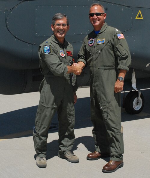 Lt. Col. Steven Edgar with the 1st Reconnaissance Squadron and Navy Cmdr. Wes Naylor from the BAMS program office at Naval Air Station Patuxent River. shake hands infornt of an RQ-4 Global Hawk during the first ever Air Force, Navy Joint Cockpit Working Group meeting, Aug. 3-5 at Beale Air Force Base. (U.S. Air Force Photo by Tech. Sgt. Luke Johnson)