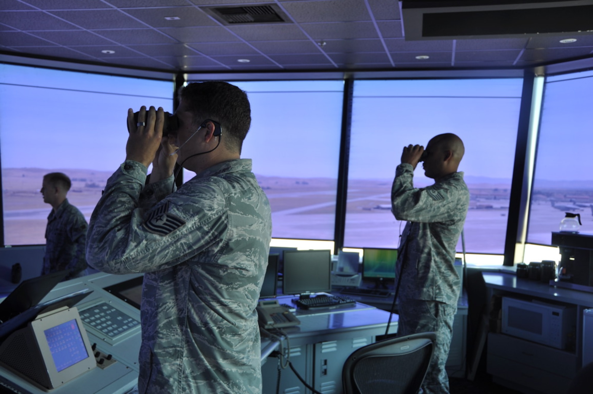 Tech. Sgt. Gerals Russell, 570th Global Mobility Readiness Squadron air traffic controller and Tech, Sgt. GreyLynn Carr, 570th GMRS air traffic controller, use binoculars July 27 to look at aircraft on the taxiway from the Air Traffic Control Tower. (U.S. Air Force photo/ Staff. Sgt. Patrick Harrower)
