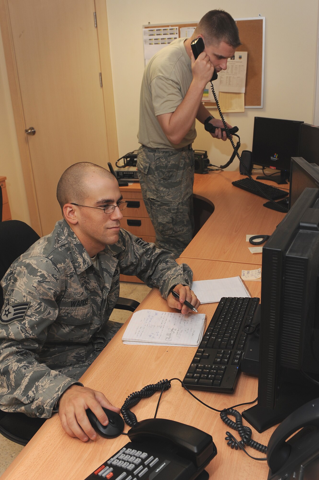 Staff Sgt. Daniel Warder (left) and Tech. Sgt Jim Sobkowiak (right), both command post controllers assigned to the 451st Air Expeditionary Wing, Kandahar Airfield, Afghanistan, confirm aircraft arrival times and record the information into a computer Aug. 6, 2010.  (U.S. Air Force photo by TSgt Chad Chisholm/Released)