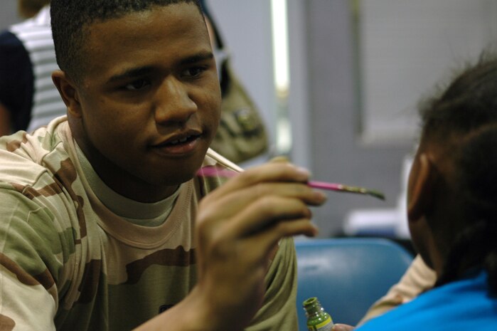 Airman 1st Class Jordan Speights, a member of the 341st Missile Security Forces Squadron, paints green hearts on the cheeks of Kadence, 7, during a children's deployment processing line at Malmstrom Air Force Base's Youth Program Center July 30, 2010. (U.S. Air Force photo/senior Airman Dillon White)