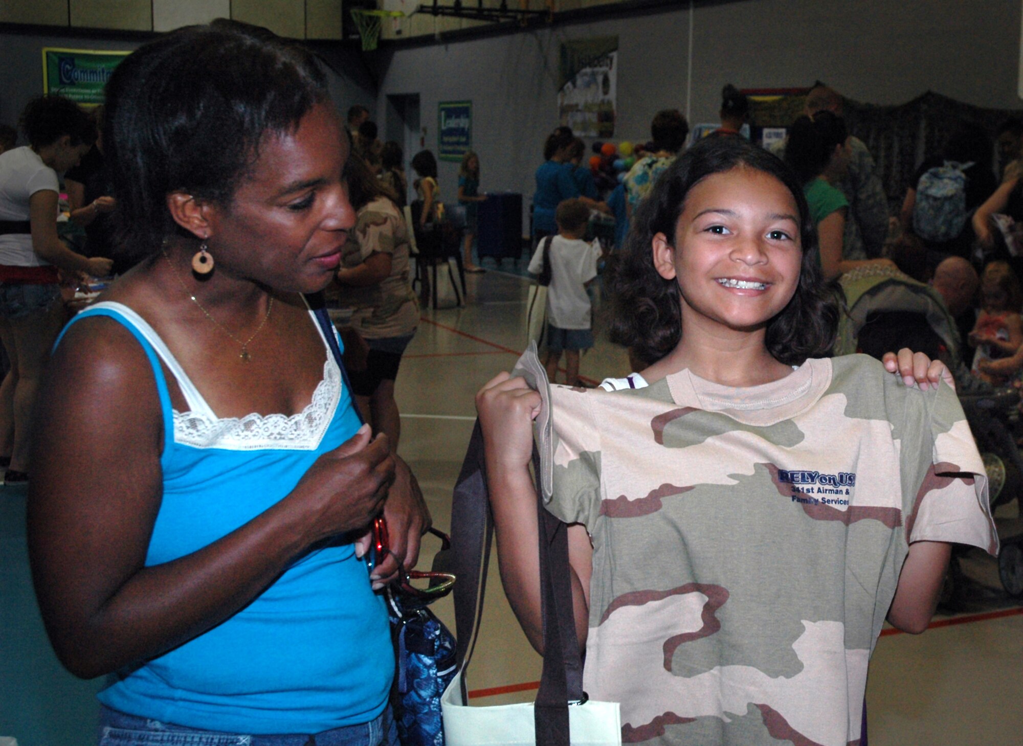 Renee Cowdery eyes her daughter, Loreal's, new shirt as Loreal smiles for a photo as the two move through a youth deployment line at the Youth Programs Center July 30, 2010. (U.S. Air Force photo/Senior Airman Dillon White)