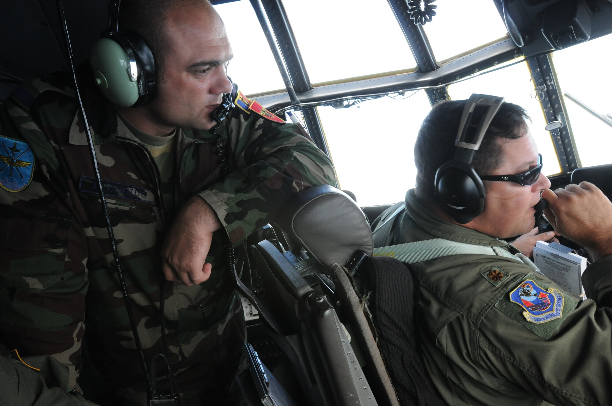 U.S. Air Force Maj. Jon Locklear, right a C-130 Hercules pilot, talks to Moldovan Lt. Col. Ion Vulpe during a medical evacuation check ride over North Carolina July 29, 2010. Vulpe is spending a week with Airmen assigned to the 156th Aeromedical Evacuation Squadron, North Carolina National Guardsmen to learn medical evacuation techniques. (DoD photo by Tech. Sgt. Brian E. Christiansen, U.S. Air Force/Released)