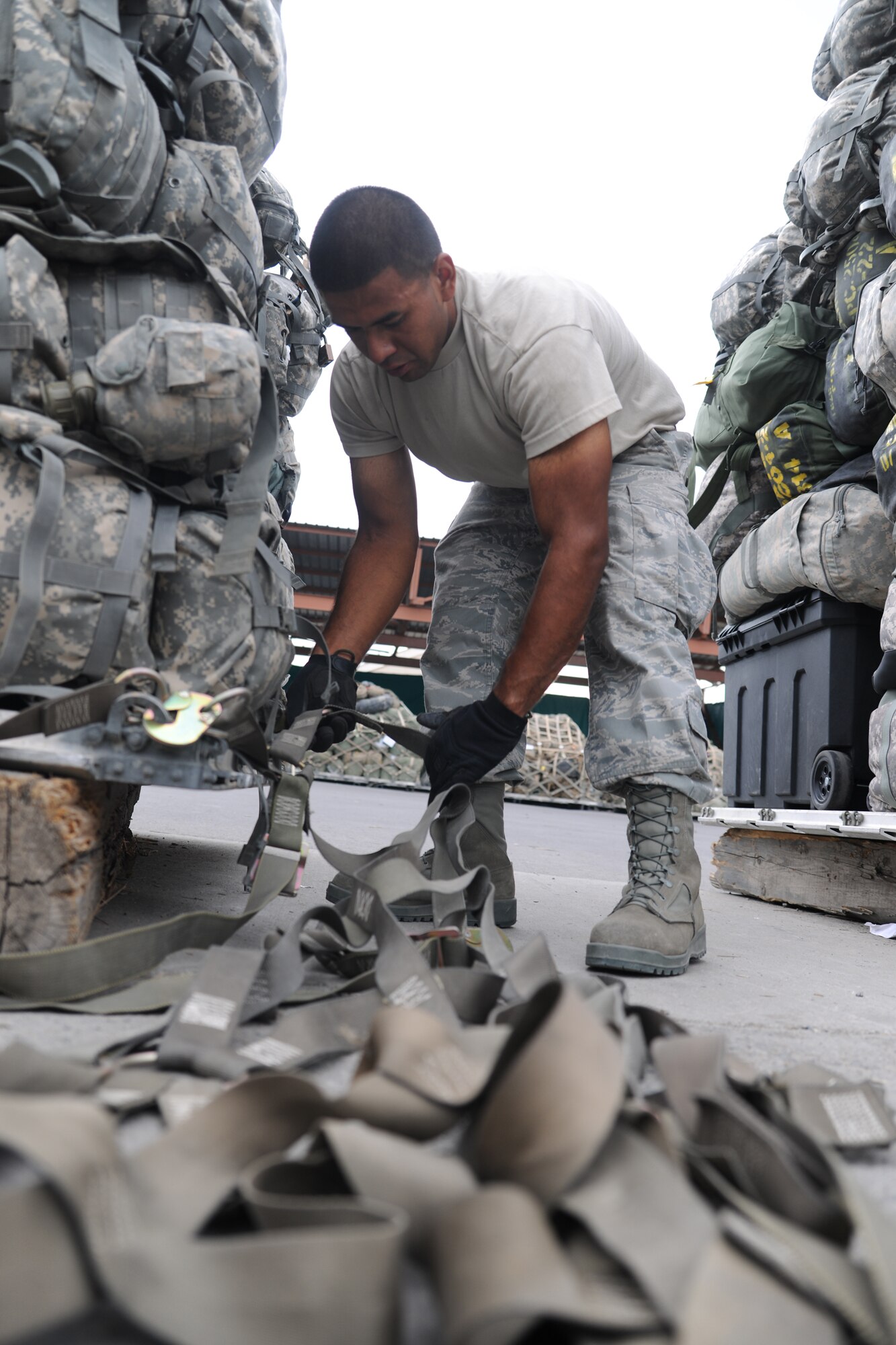 TRANSIT CENTER AT MANAS, Kyrgyzstan - Airman First Class Heriberto Dominguez, 376th Expeditionary Logistics Readiness Squadron passenger service agent, connects cargo straps onto pallets for transportation onto a C-17 Globemaster III Aug. 6.  With the nickname "Yard Dogs," he assists in building an upward of 15 pallets a day taking about 10 minutes per pallet.  (U.S. Air Force photo/Staff Sgt. Nathan Bevier)