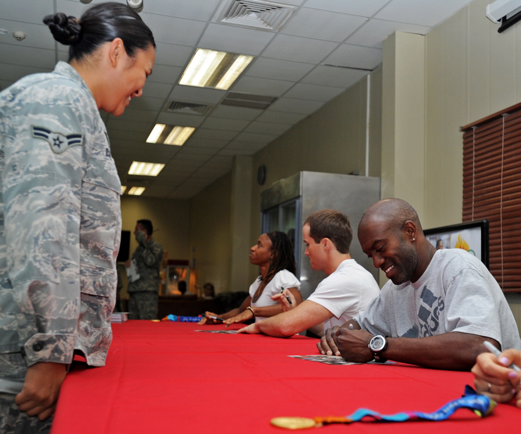 SOUTHWEST ASIA -- Allen Johnson, 1996 Olympic 110-meter hurdles gold medalist, autographs flyers for Airmen at an undisclosed air base here Aug. 4, 2010. Johnson was one of four gold medalists to visit the 386th Air Expeditionary Wing. Also in attendance were runner Moushaumi Robinson, 2004 Olympic 4x400 meter relay gold medalist; Paul Hamm, 2004 Olympic all-around gymnastics champion and gold medalist; and swimmer Carly Piper, 2004 Olympic 4x200 meter freestyle relay gold medalist. (U.S. Air Force photo by Senior Airman Laura Turner)