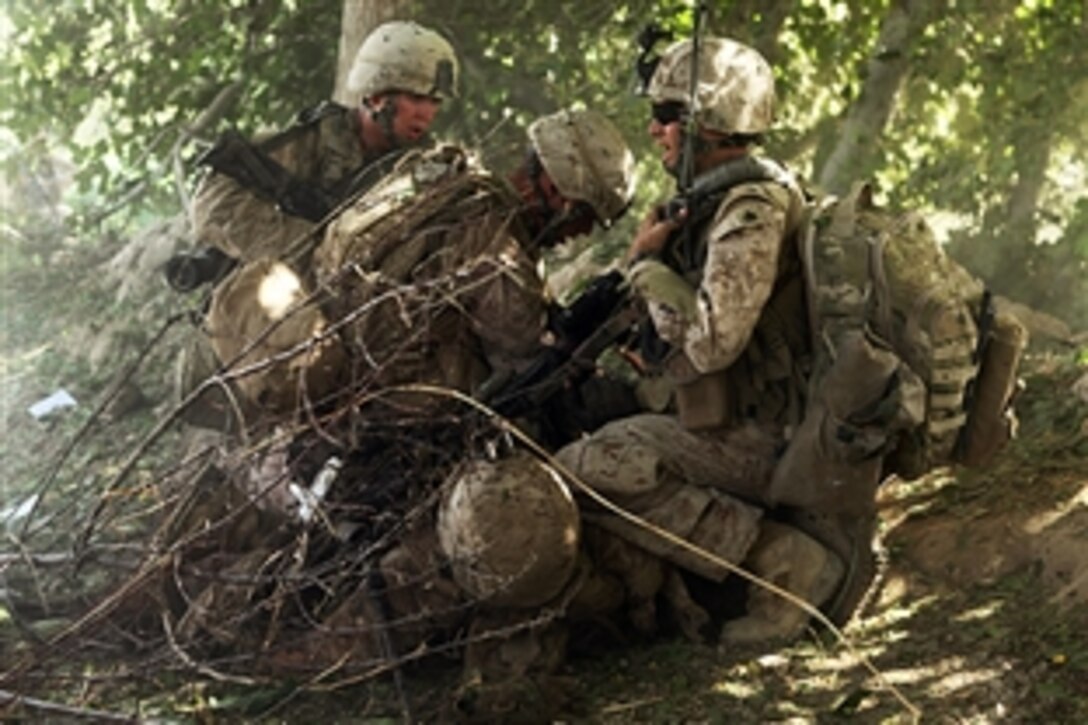 A U.S. Navy corpsman and Marines work on an injured Marine while concealed in brush and trees in Sangin, Afghanistan, July 22, 2010. The injured Marine stepped on an improvised explosive device, but was saved through the fast reaction of those around him.