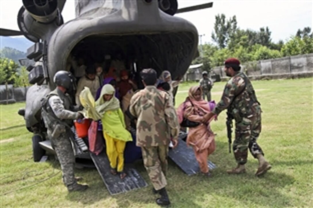 A U.S. Army soldier and Pakistani troops help Pakistani residents as they disembark from a U.S. Army helicopter in Khwazahkela, Pakistan, as part of relief efforts to help flood victims, Aug. 5, 2010. Recent heavy rains forced thousands of residents to flee rising floodwaters. U.S. forces have partnered with the Pakistani military to coordinate evacuation and relief efforts.
