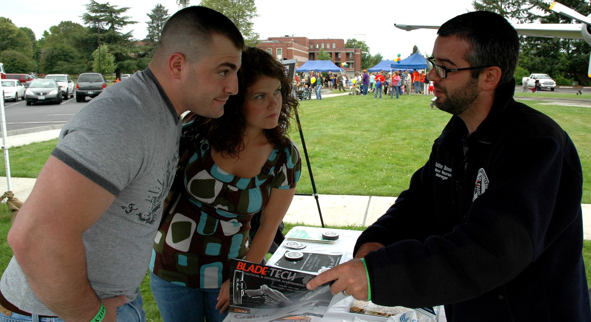 JOINT BASE LEWIS-MCCHORD, Wash.- Colin Brooks, (right) Adventures Unlimited manager at McChord Field here, explains some of the upcoming outdoor recreation events to Senior Airman Angela Leonardo, 313th Airlift Squadron and her husband Michael. Adventures Unlimited was one of the information booths that showcased its services and products during the 446th Airlift Wing's annual Family Day at Heritage Hill Aug. 7. (U.S. Air Fore photo/Staff Sgt. Nicole Celestine)