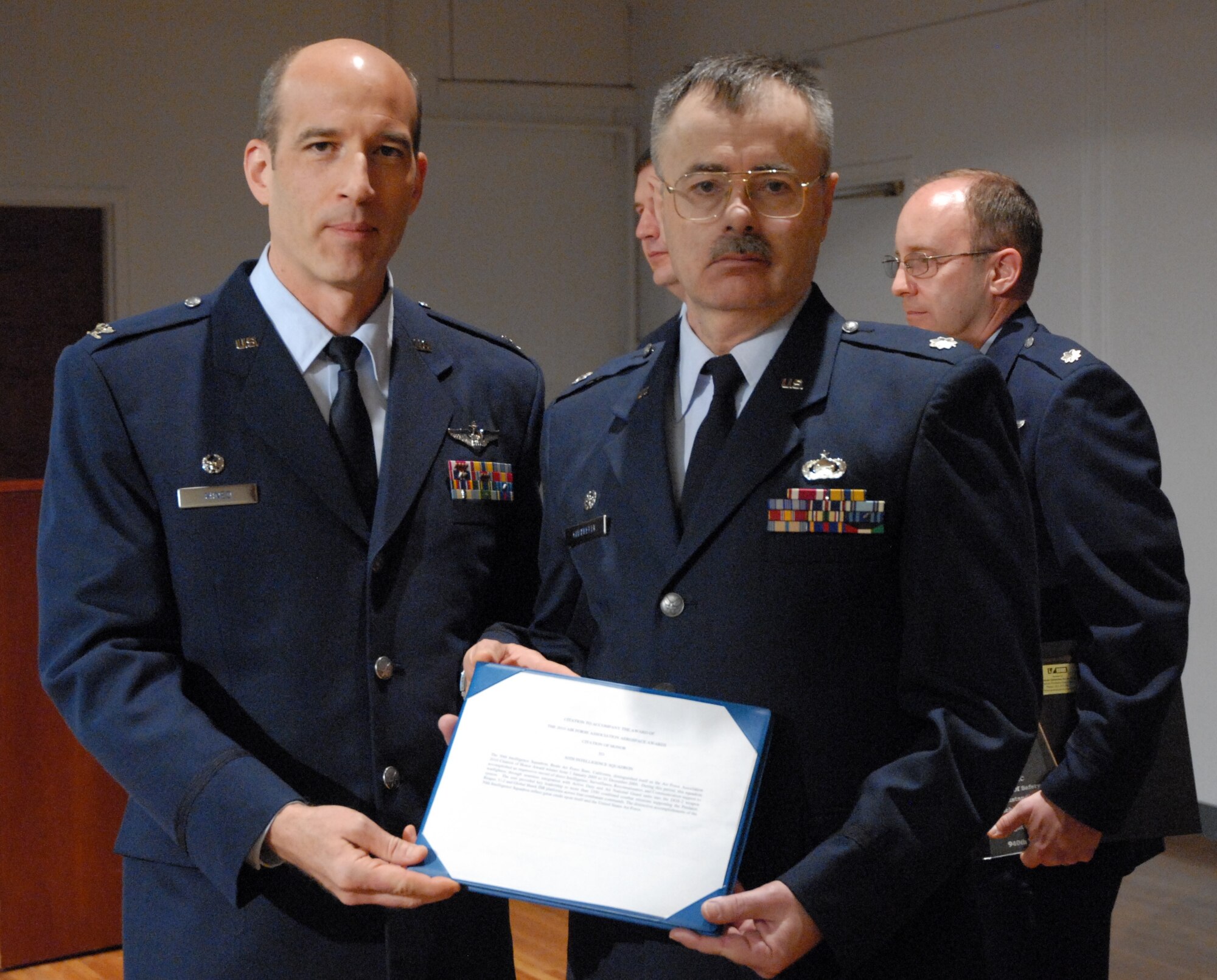 Lt. Col. Kenneth Chappelle, 50th Intelligence Squadron commander, receives the Air Force Reserve Command's Outstanding Intelligence Unit of the Year award from Col. Jeffrey Mineo, 940th Wing commander, during commander's call, March 7, at the Community Activity Center, Beale Air Force Base, Calif. The 50 IS also won company grade officer, NCO and Airman ISR of the Year awards. (U.S. Air Force photo/Tech. Sgt. Kenneth McCann)
