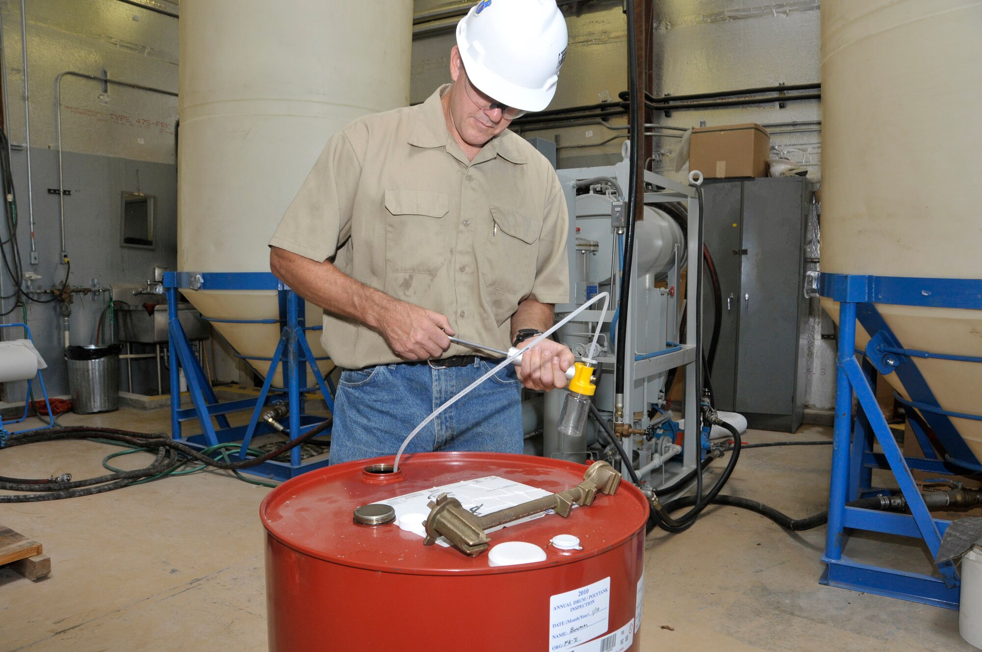 Mike Bowman, ATA outside machinist, prepares a portable processing unit at the Oil Processing Facility prior to deployment. These small units are delivered to a piece of equipment to remove water and particulate contamination from its oil without removing the oil from the equipment. In the background can be seen a 1,600-gallon cone-bottomed vertical tank used to contain the oil as it is processed. (Photo by Rick Goodfriend)
