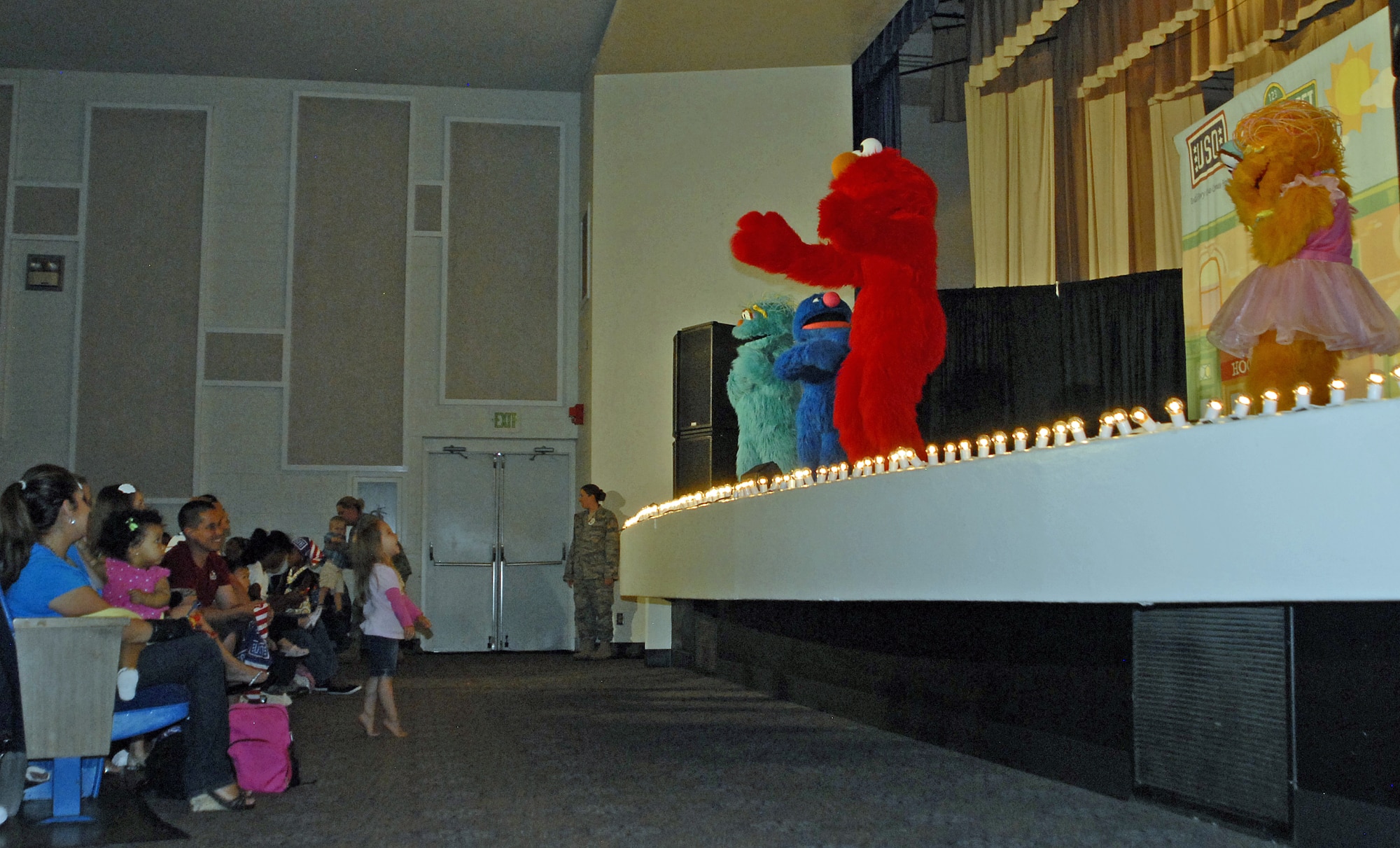 A young girl watches from the front row of the Sesame Street show as Elmo sings songs with his friends.  The Sesame Street/USO Experience for Military Families performance took place at the Peterson Air Force Base auditorium July 31 and was exclusively for military families.  (U.S. Air Force Photo/Airman 1st class Jessica Hines)