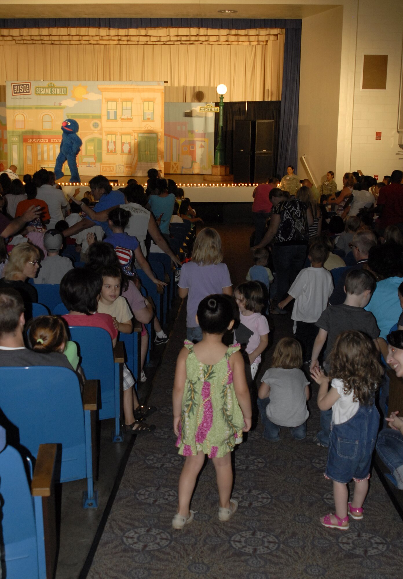 Children dance and sing along in the aisles of the Peterson Air Force Base auditorium July 31, at the Sesame Street/USO Experience for Military Families show. Elmo and his friends encouraged children and parents to sing along as they thought of ways to pass the time when a parent has to go away for their job. (U.S. Air Force Photo/Airman 1st class Jessica Hines)
