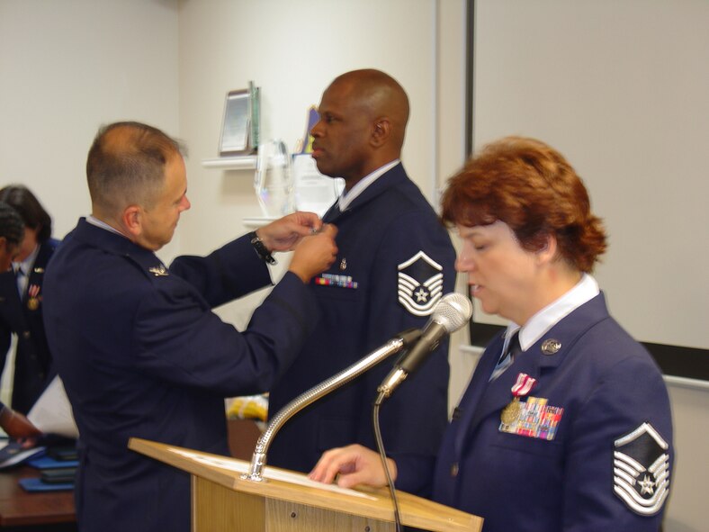 WRIGHT-PATTERSON AIR FORCE BASE, Ohio – Col. Oba Vincent, 445th Aeromedical Staging Squadron commander, pins the Air Force Achievement Medal to the service coat of Master Sgt. Darrell Lawrence during their unit’s award ceremony Aug. 8 as Master Sgt. Melanie LaLiberty reads the order. (U.S. Air Force photo/Maj. Mary Reed)