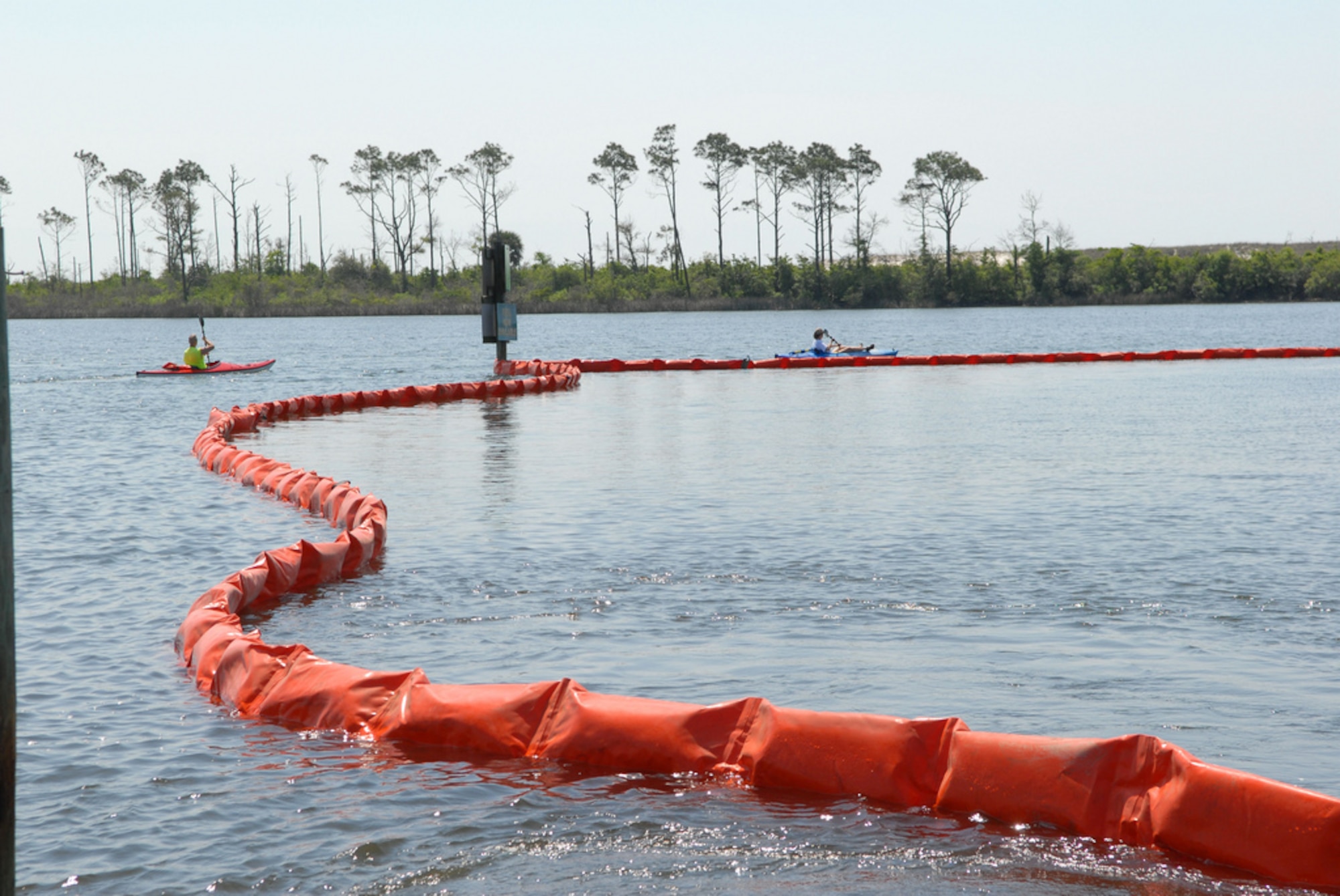 NAS PENSACOLA, Fla. (May 4, 2010) Kayakers at Naval Air Station Pensacola detour around oil containment boom at Sherman Cove aboard the base. The boom was set to protect environmentally sensitive grass beds from the Deepwater Horizon oil spill. Deepwater Horizon was an ultra-deepwater oil rig that sank April 22, causing a massive oil spill threatening the U.S. Gulf Coast. (U.S. Navy photo by Patrick Nichols/Released)  