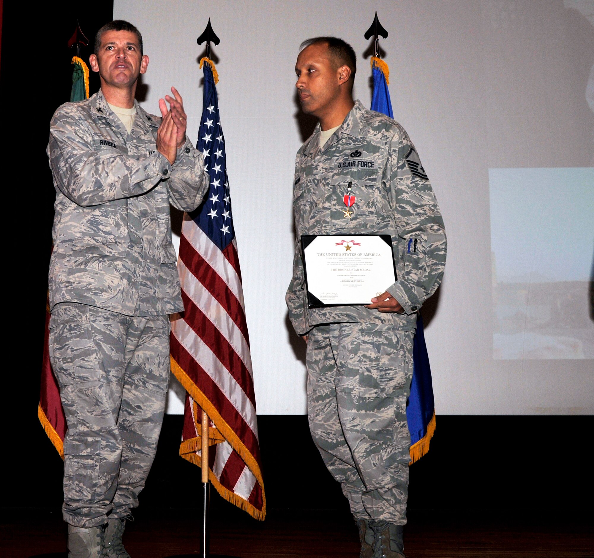 Col. Jose Rivera, 65th Air Base Wing commander, applauds Master Sgt. Rigoberto Chacon, 65th Civil Engineer Squadron, after presenting him with a Bronze Star and a certificate during a ceremony here Aug. 6. Sergeant Chacon earned the medal during his deployment to Afghanistan, where he led his teams to 40 forward operating bases and bedded down over 40,000 combat forces.  (U.S. Air Force photo/Staff Sgt. Olufemi Owolabi)  