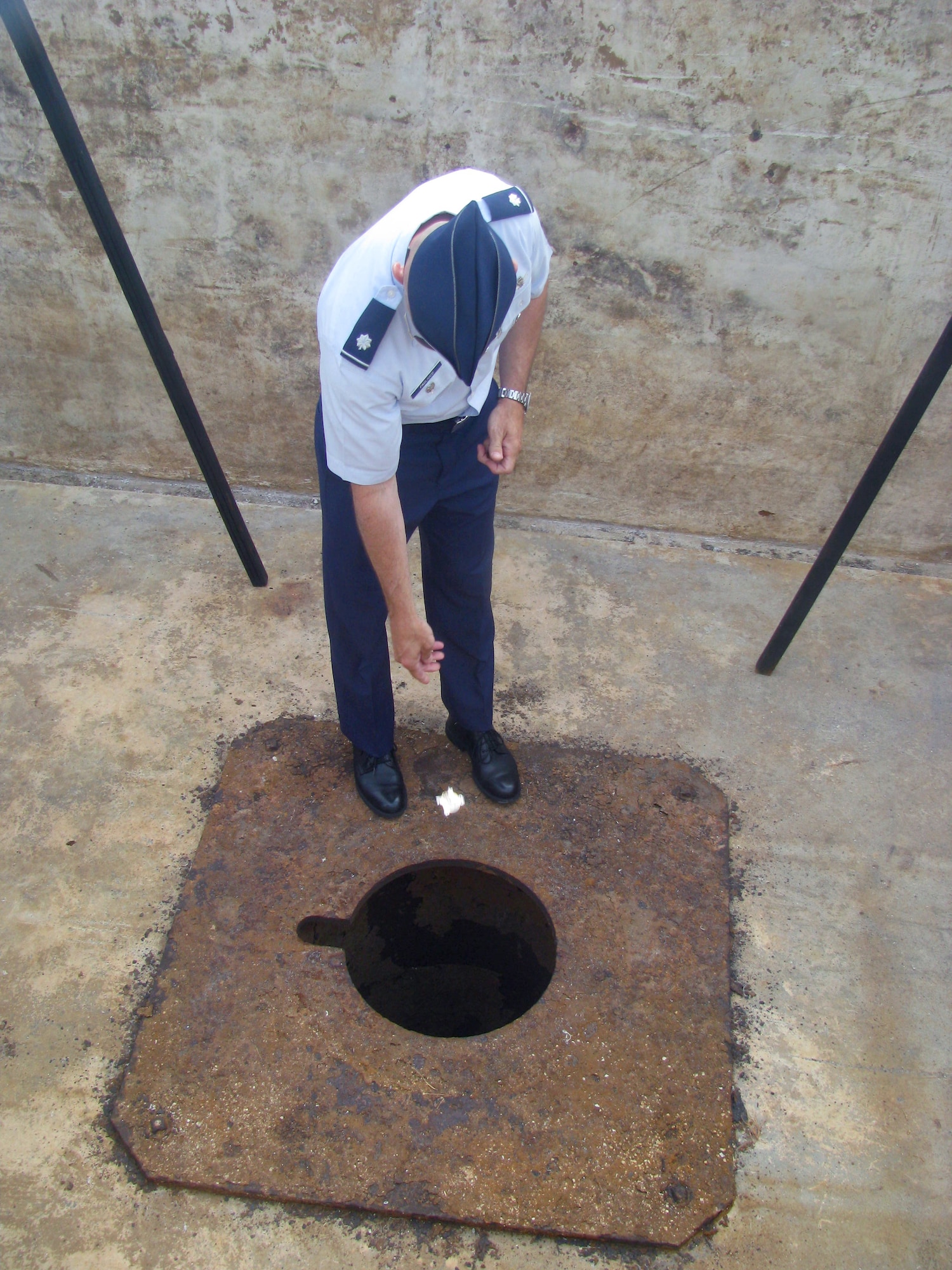 Lt. Col. Richard Pagliuco drops a 20th Air Force coin in the pit used to load atomic bombs onto B-29 Superfortresses at the end of World War II, shortly before a wreath-laying ceremony Aug. 6, 2010, in Tinian, Commonwealth of Northern Northern Mariana Islands. Local officials invited him and a 509th Bomb Wing representative to place unit coins in the bomb pit during a commemoration of Tinian's role in World War II. Colonel Pagliuco is the 20th Air Force deputy director of operations at F.E. Warren Air Force Base, Wyo. (U.S. Air Force photo/Lt. Col. Sam Highley)
