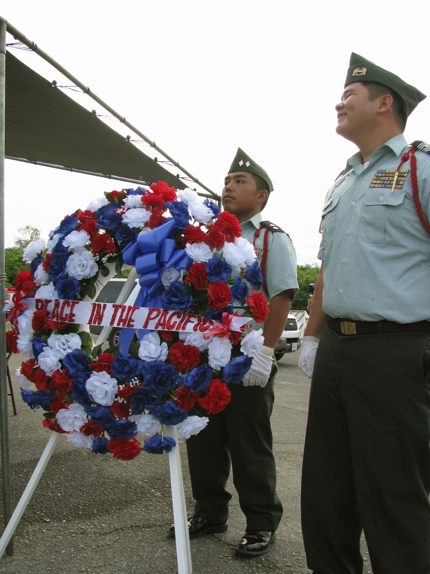 Joel Santos (left) and William Manglona stand by a wreath commemorating the end of World War II shortly before a ceremony Aug. 6, 2010, in Tinian, Commonwealth of Northern Northern Mariana Islands. The two Junior R.O.T.C. cadets from Tinian High School placed the wreath by pits designed to load atomic bombs onto B-29 Superfortresses at the end of World War II, as part of a commemoration of Tinian's role in the war. (U.S. Air Force photo/Lt. Col. Sam Highley)